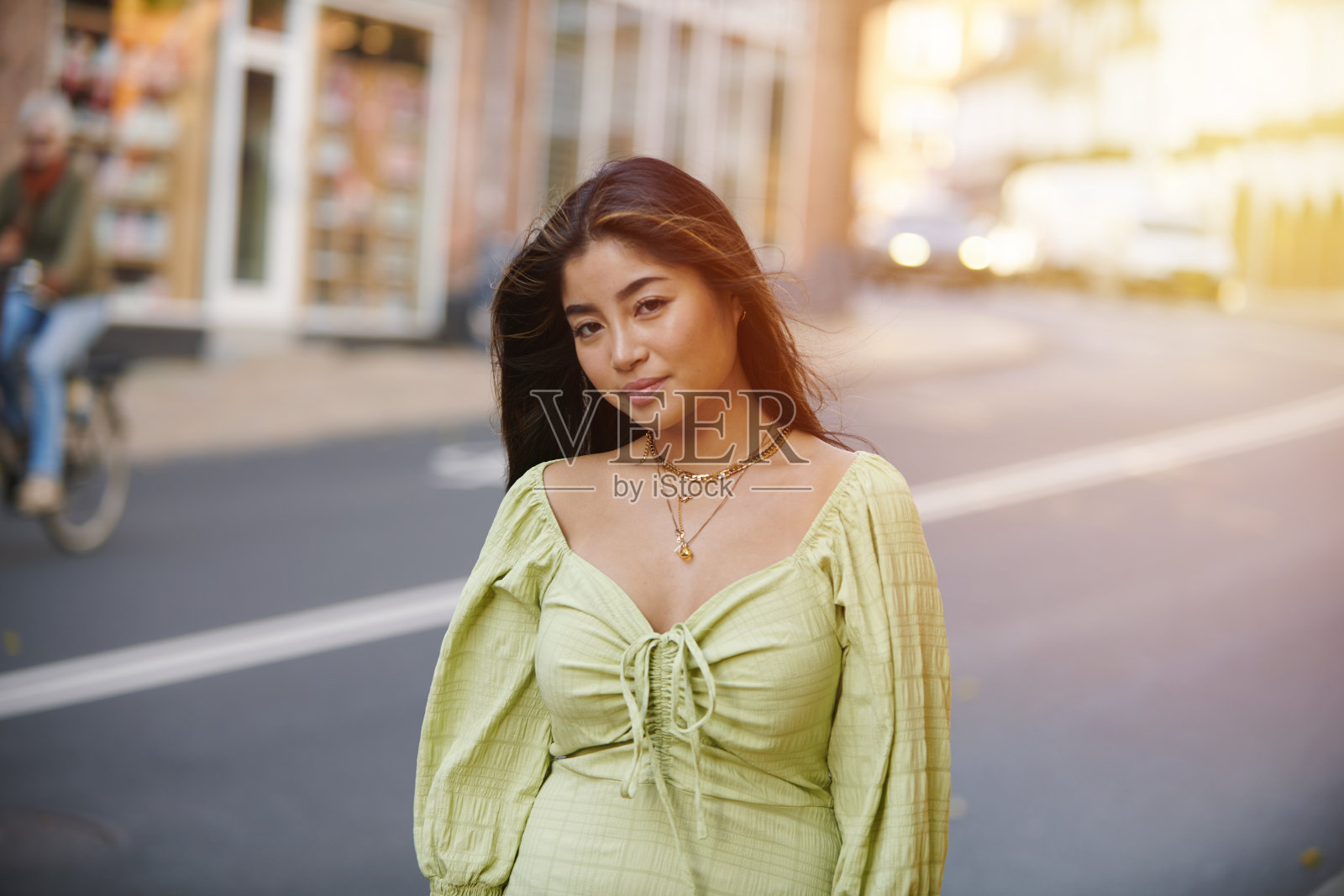 年轻的亚洲女子穿着绿色的衣服走在街上照片摄影图片