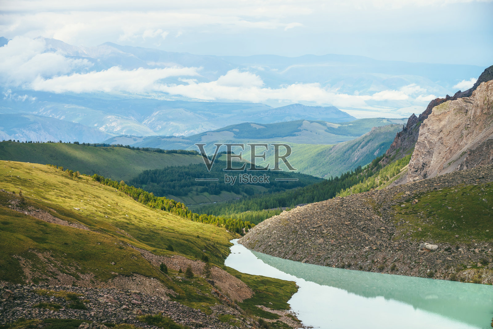 色彩斑斓的绿色景观与美丽的绿松石山湖在阳光下。令人印象深刻的风景与绿松石湖的背景与森林和低云的绿色山脉。风景优美的山。照片摄影图片