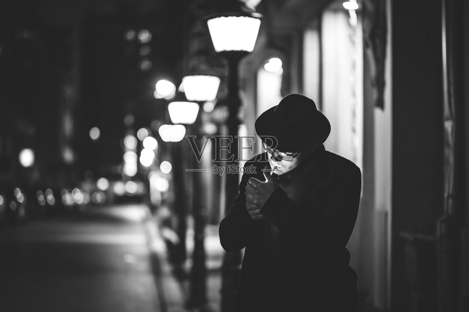 戴着帽子的英俊男子在城市街道上点燃香烟照片摄影图片