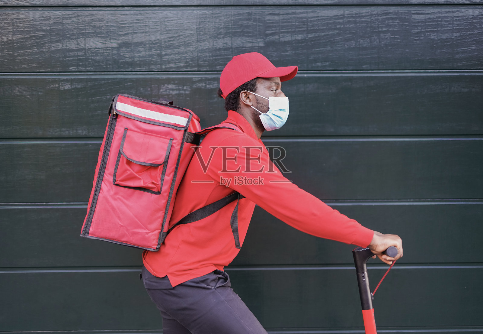 非洲送餐员骑着电动滑板车，戴着口罩应对冠状病毒爆发照片摄影图片