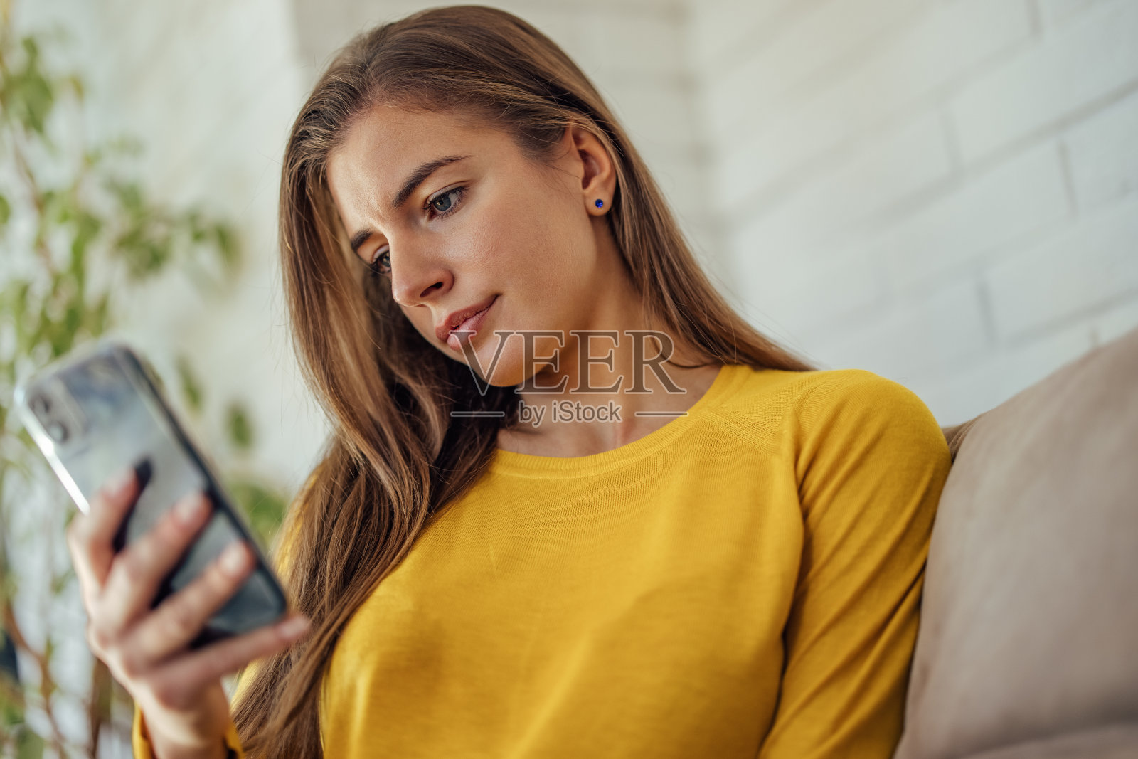 一个小女孩，在室内用手机。照片摄影图片