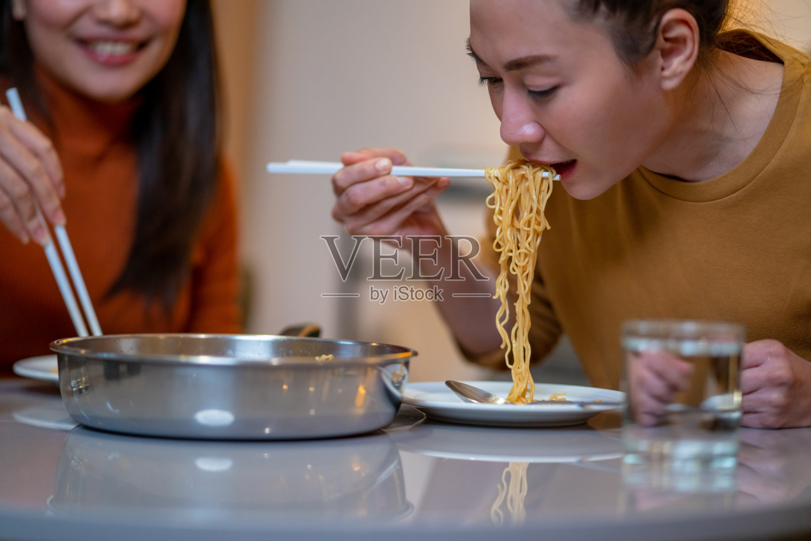 亚洲女性朋友在家里一起吃拉面和香肠照片摄影图片