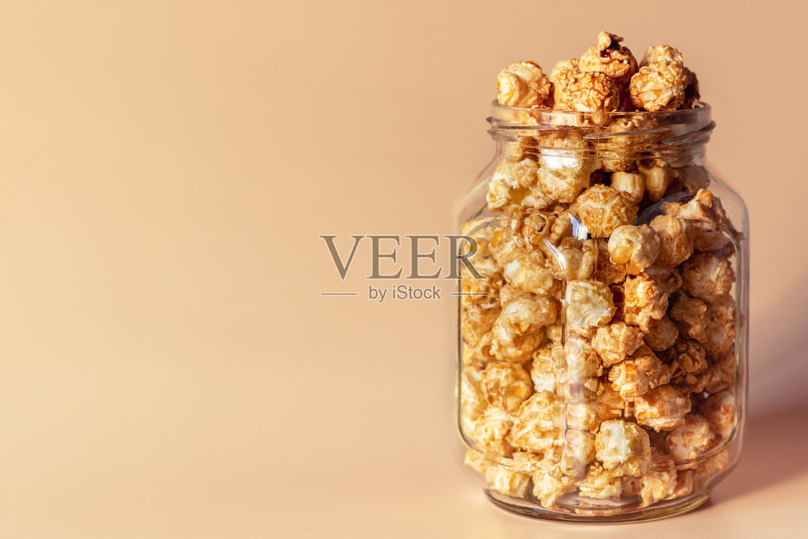 焦糖爆米花放在玻璃罐里，背景上有文字照片摄影图片