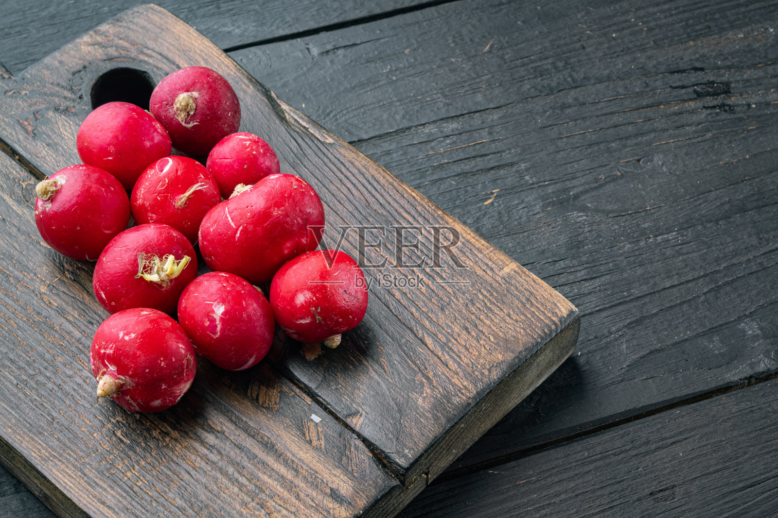 一束束成熟的萝卜，放在木制砧板上，黑色木桌背景上，有文字和文字的空间照片摄影图片