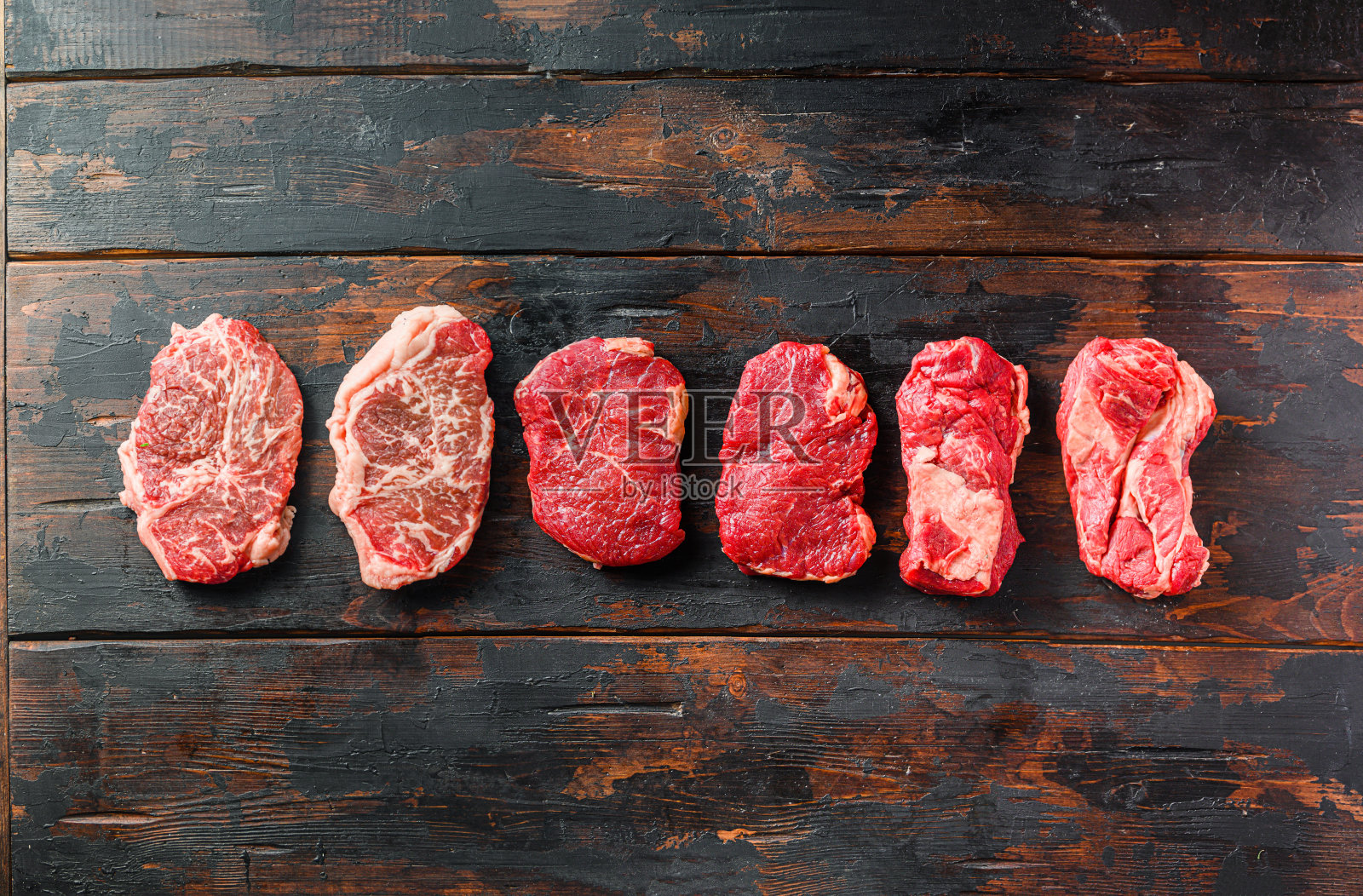 一套不同类型的生牛排:顶部刀片，臀部，chuckeye滚动旧木制背景顶部视图空间的文本。照片摄影图片