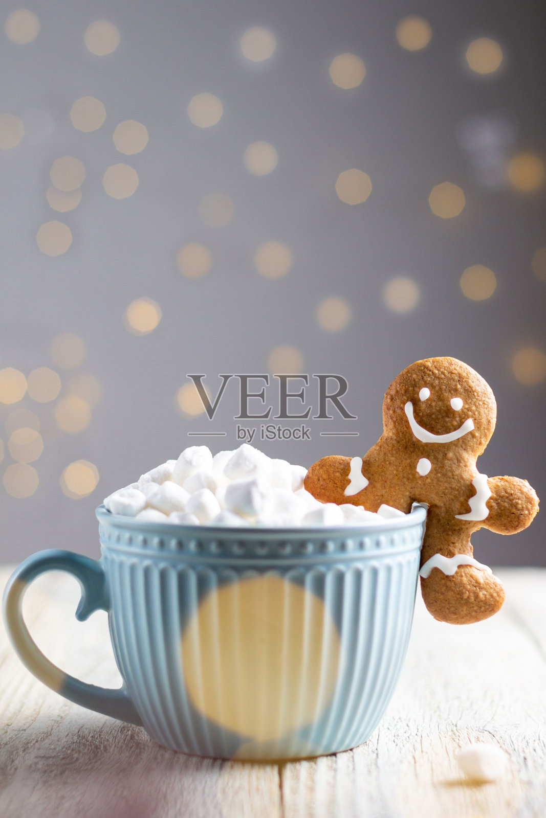 一杯蓝色的冬季热饮，里面有棉花糖和姜饼人，背景是白色的木头。照片摄影图片