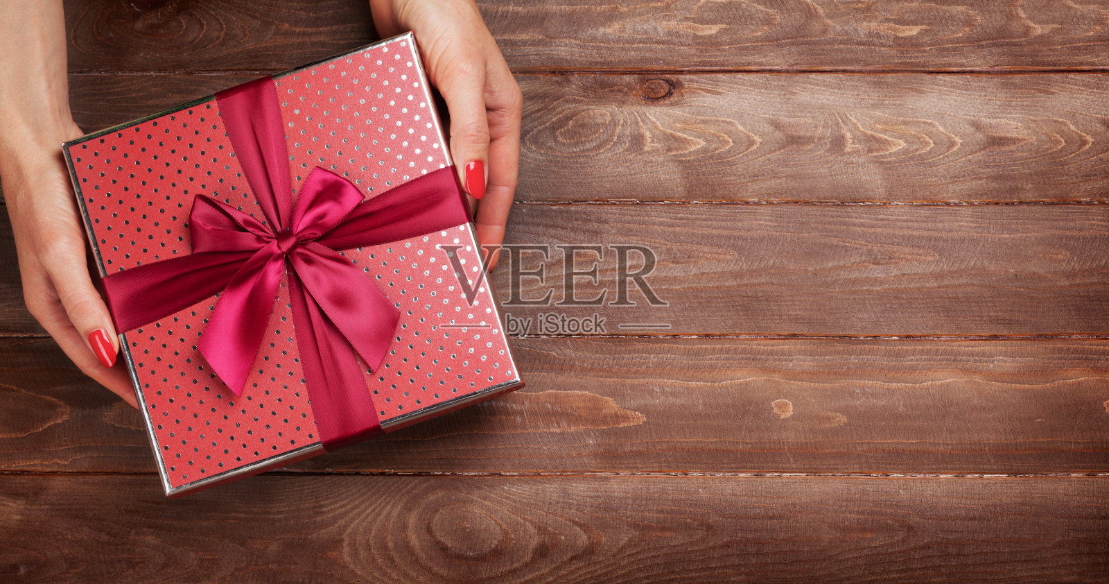 木制桌子上方，女性手拿礼物照片摄影图片
