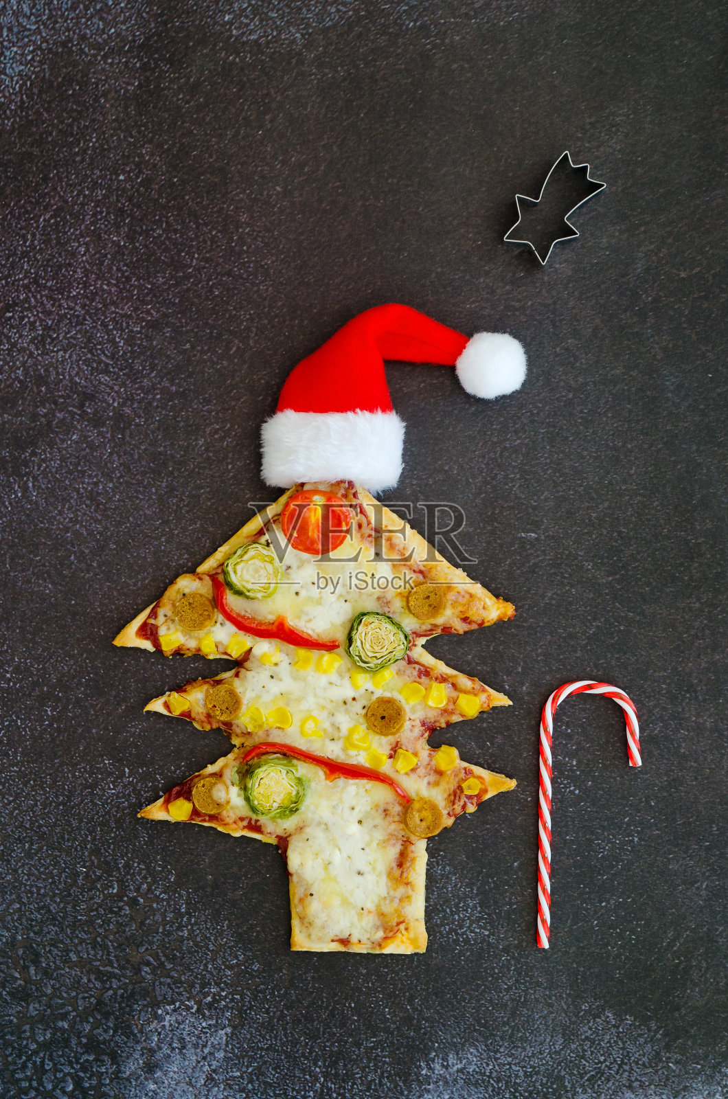 美味的素食圣诞树披萨，黑色背景上有西红柿，奶酪，蔬菜。创意，有趣的食物概念的孩子。俯视图，平躺。副本的空间。照片摄影图片