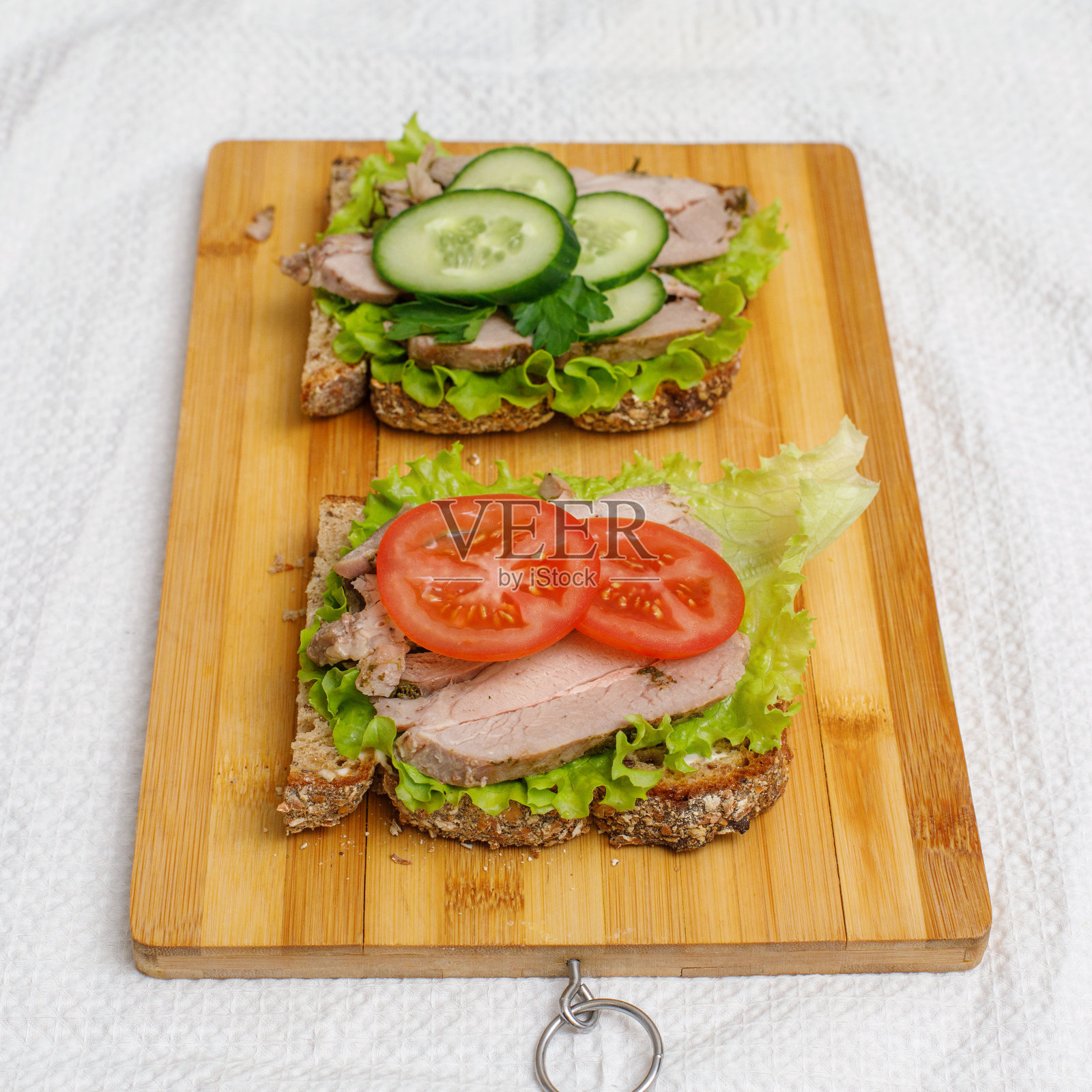 新鲜的三明治和烤好的肉和蔬菜放在砧板上照片摄影图片