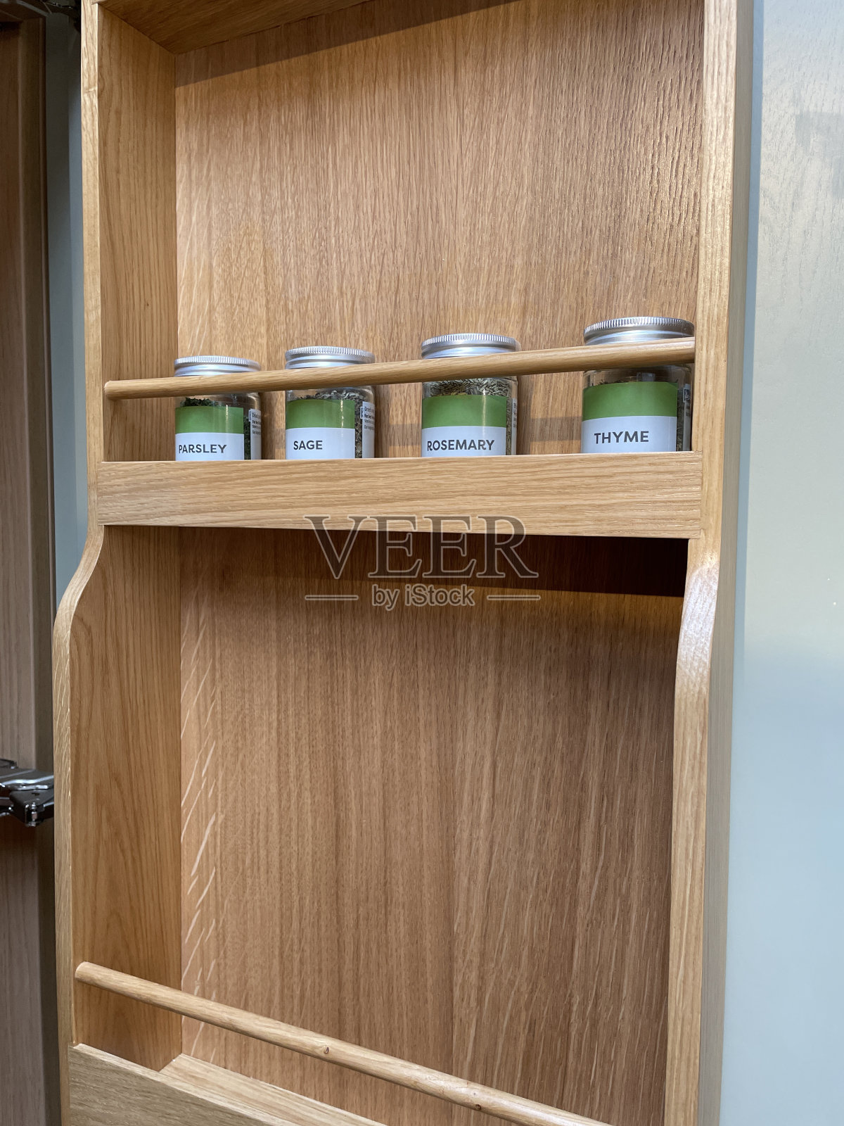 近景现代厨房，木制，壁挂式药草架，货架存储与排标签药草罐，欧芹，鼠尾草，迷迭香和百里香照片摄影图片