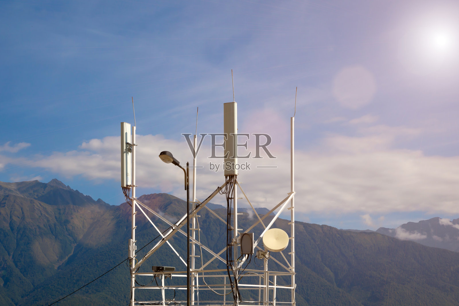 电信传输4G, 5G。山脉背景公路附近带有发射机天线的蜂窝基站。照片摄影图片