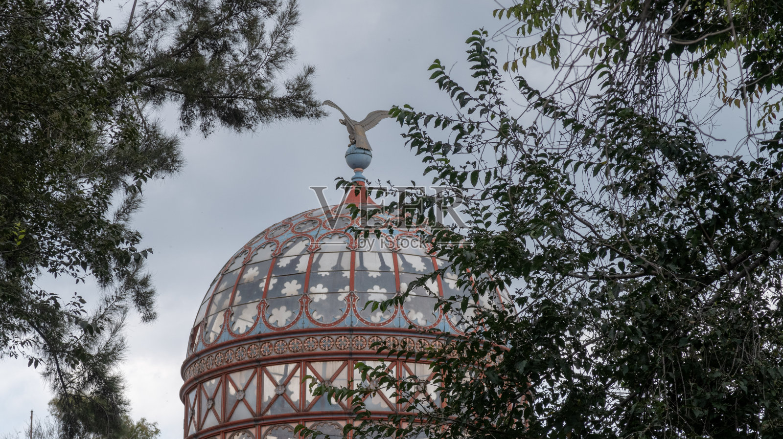 摩尔风格的亭子在树之间，顶部有老鹰雕塑照片摄影图片