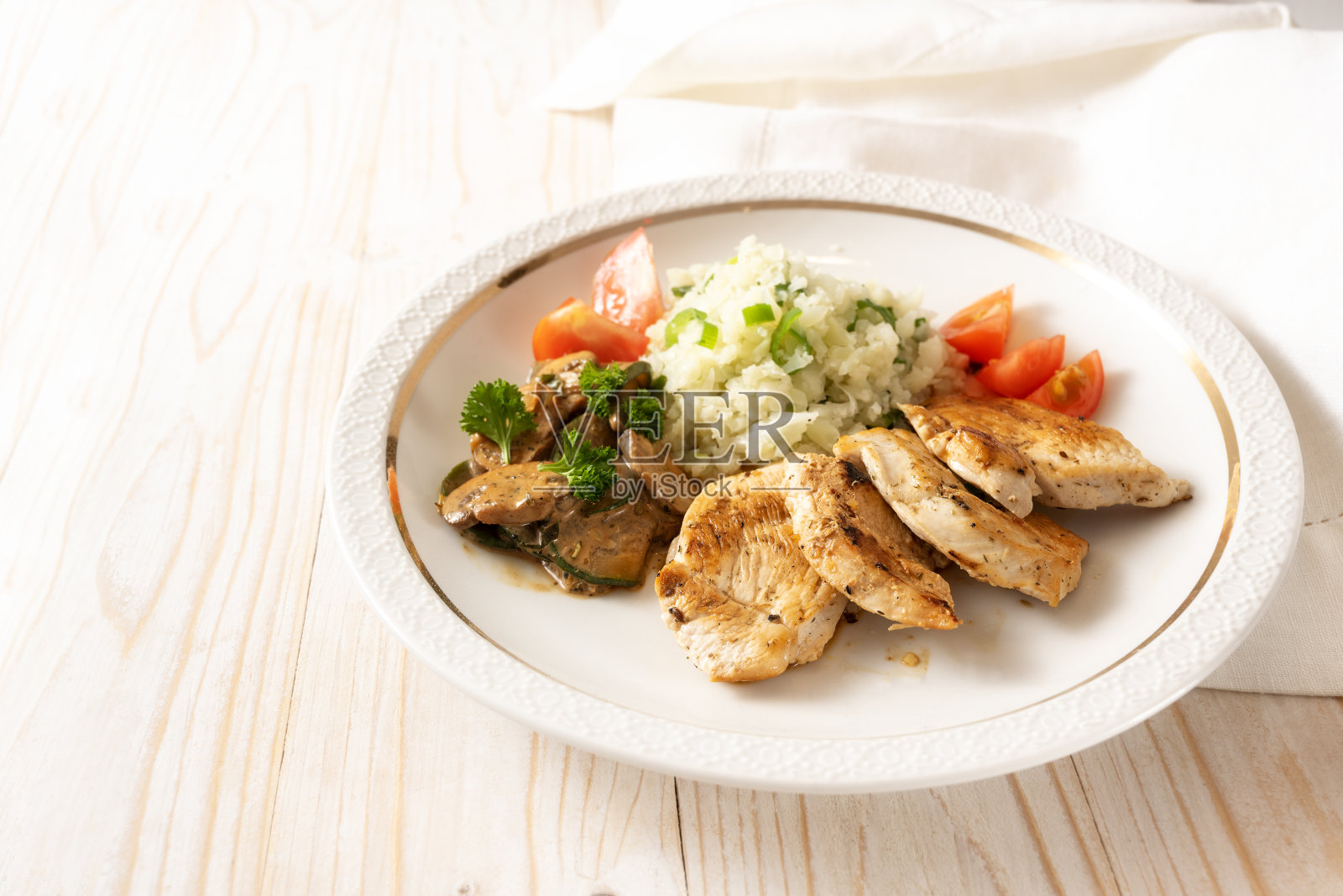 低碳水化合物饮食与炸鸡，花椰菜饭，蘑菇烩和西红柿在一个白色的盘子和一个轻便的木桌，复制空间，选定的重点照片摄影图片