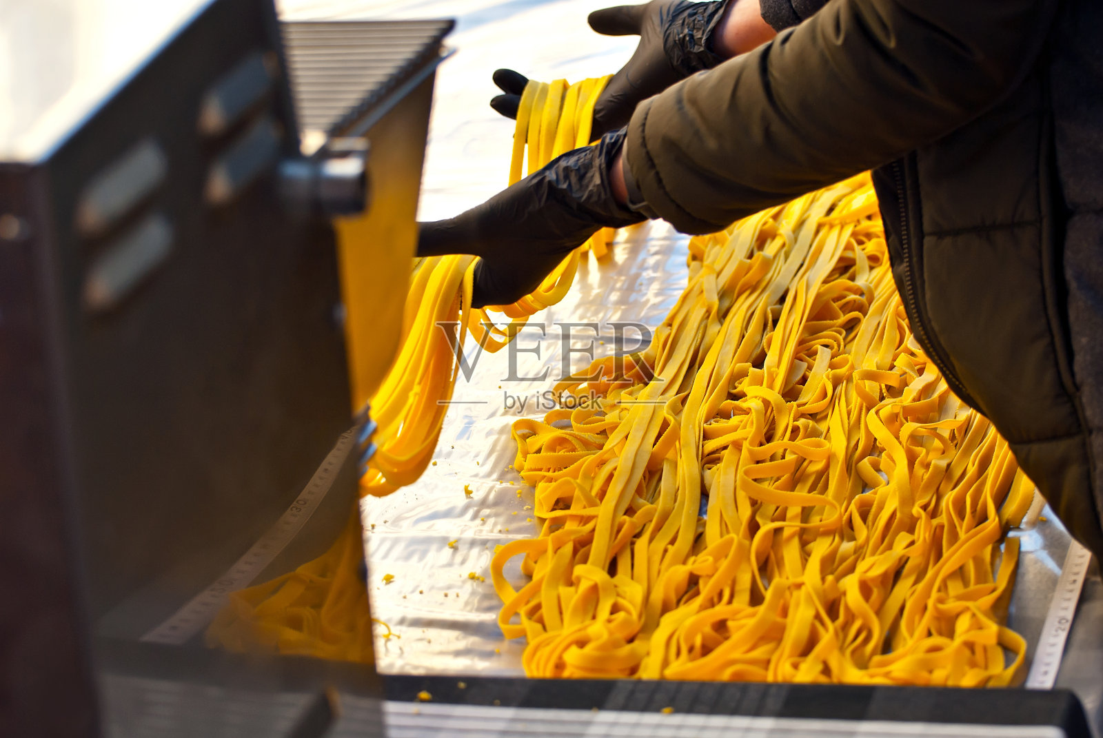 展销会上的意大利面制作示范。创造了世界上最长的意大利面。黄色的长面摊在桌上。照片摄影图片