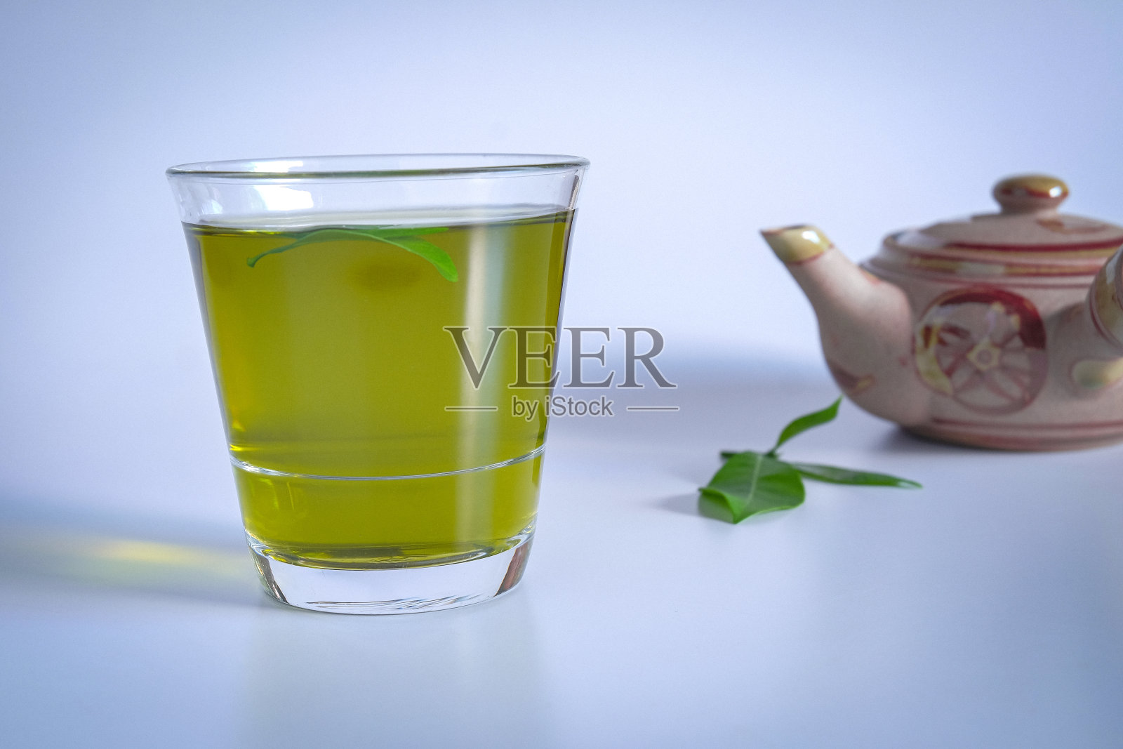 热腾腾的绿茶，加上茶叶和古老的茶壶泥。照片摄影图片