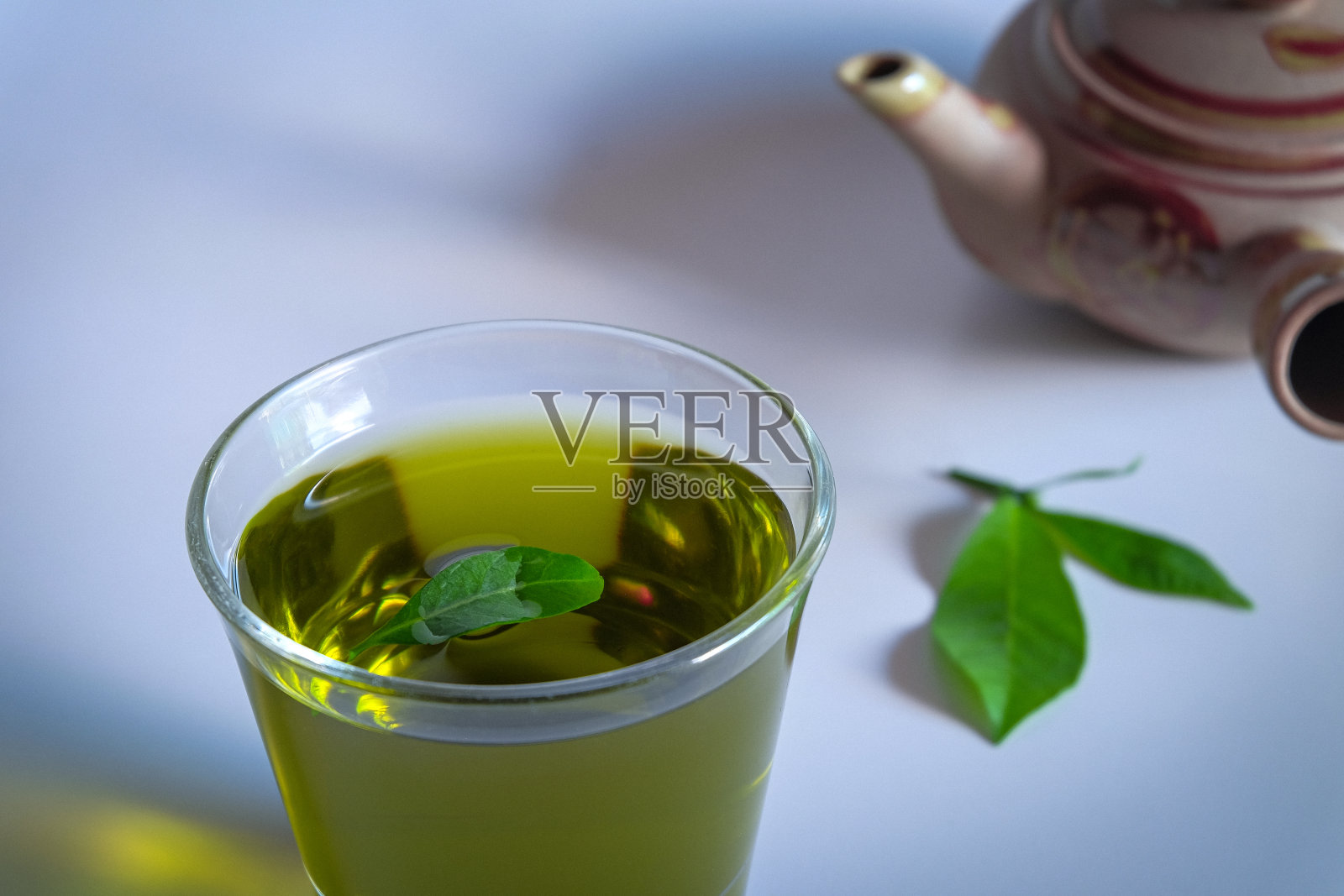 热腾腾的绿茶，加上茶叶和古老的茶壶泥。照片摄影图片