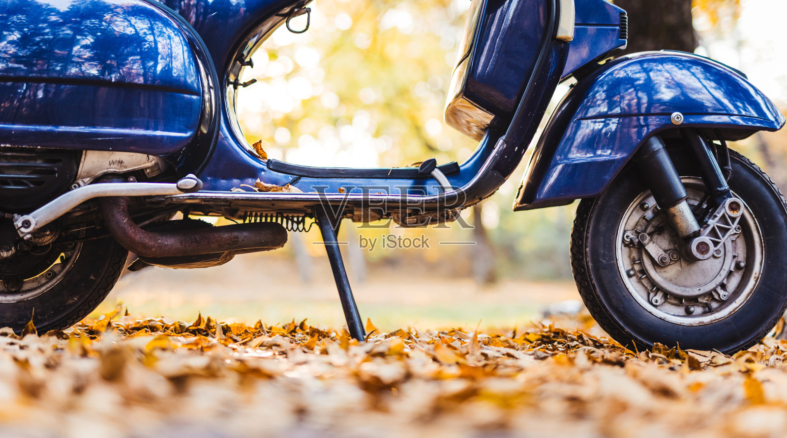 部分复古摩托车停在秋叶上照片摄影图片