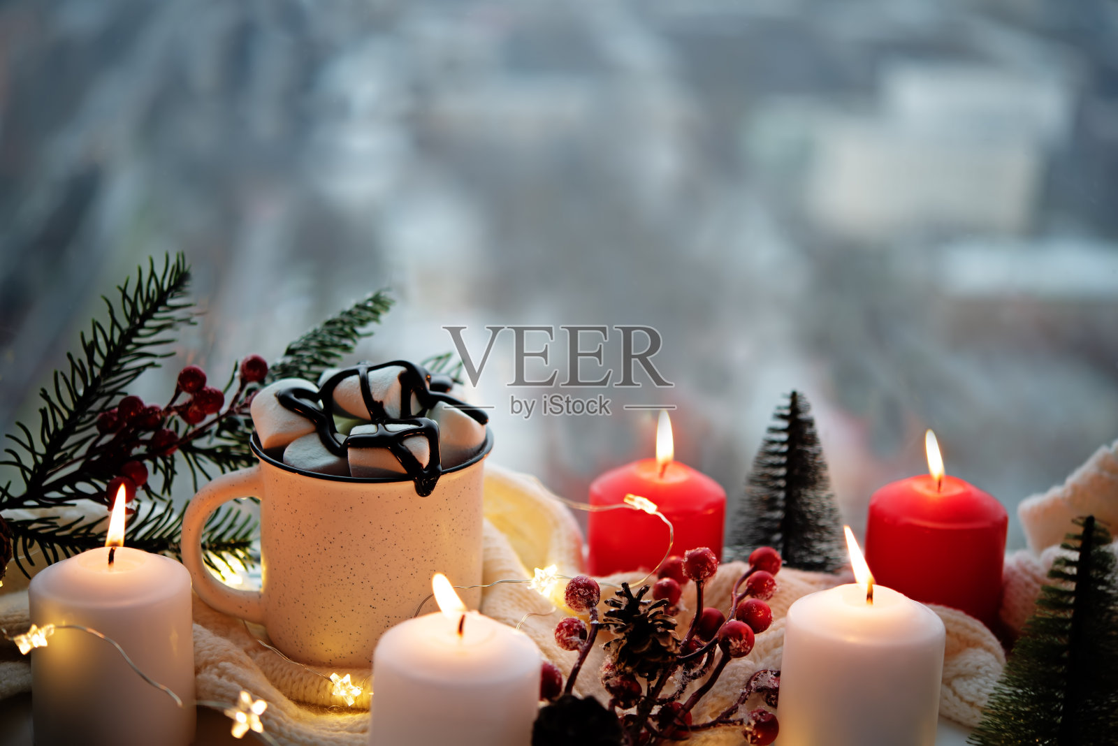 冬天圣诞假期背景有蜡烛;圣诞灯;一杯加棉花糖的可可或靠近窗户的热巧克力照片摄影图片
