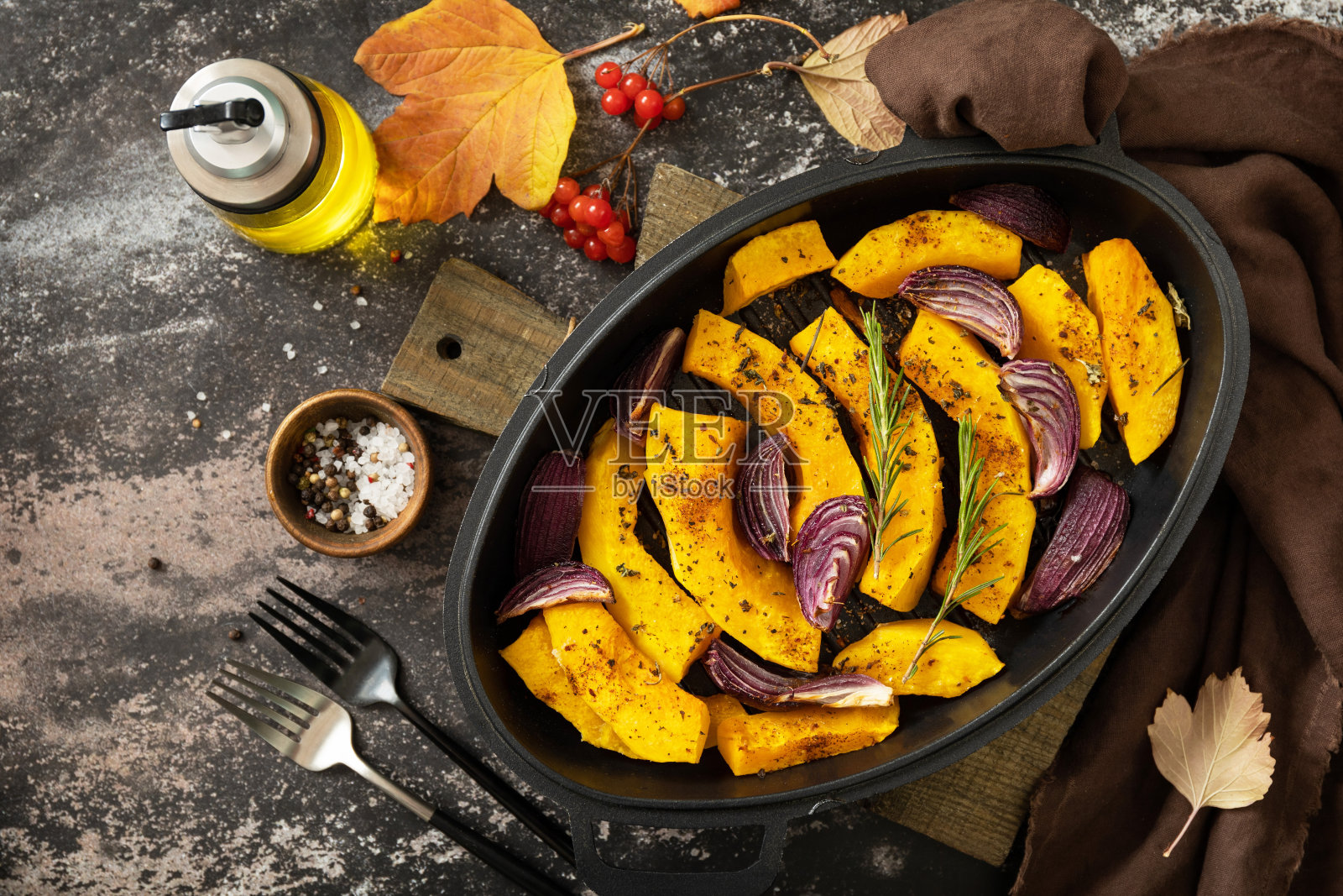 南瓜片配迷迭香和紫洋葱，在深色的石头背景下烘烤新鲜的健康食品。生酮或旧石器饮食素食或素食者。俯视图平面背景。照片摄影图片