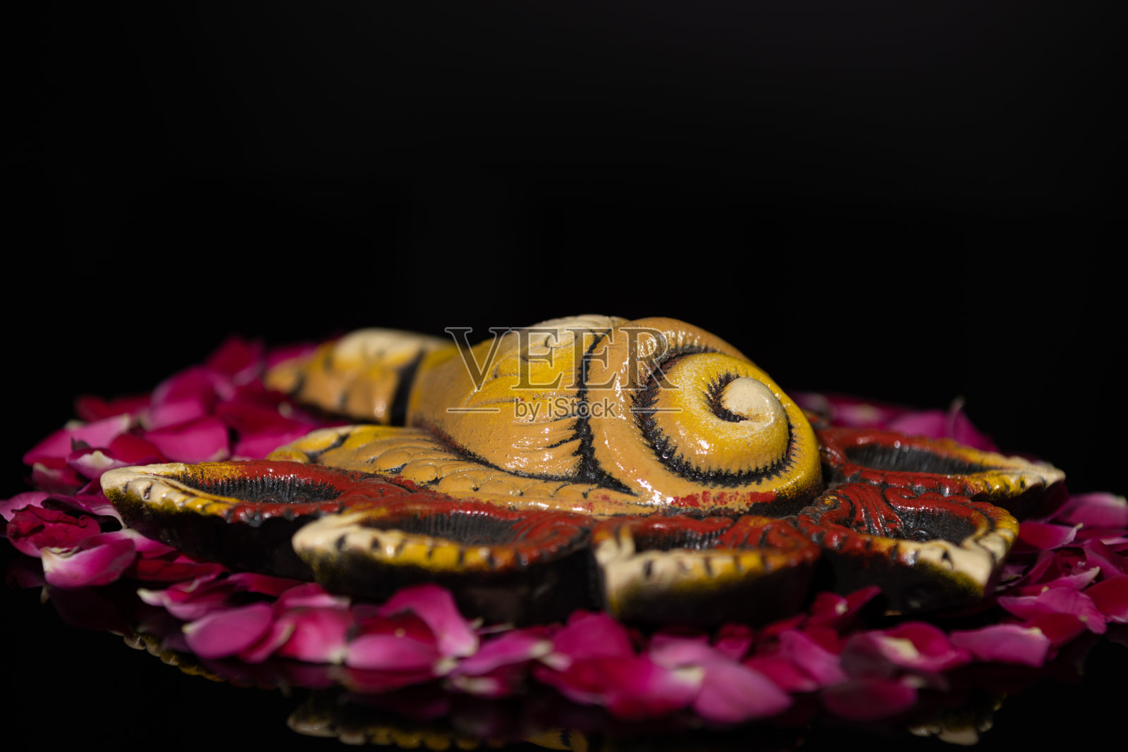 环保粘土Shankh Diya Deep Dia布置在玫瑰花瓣上作为rangoli背景与复制空间照片摄影图片