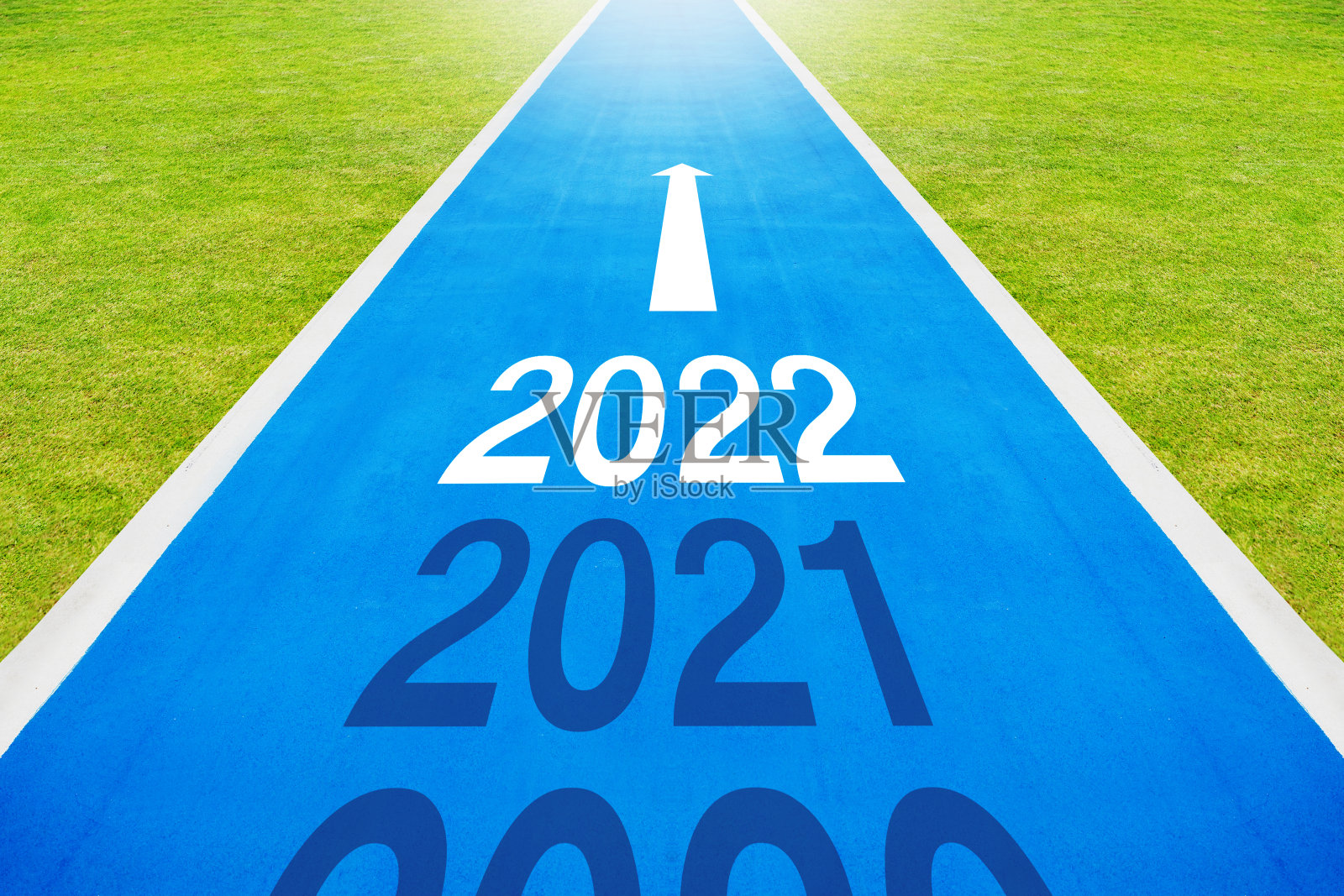 在空旷的蓝色柏油路上，自行车道上写着2021-2022这个数字。健康，迎接2022年新年照片摄影图片