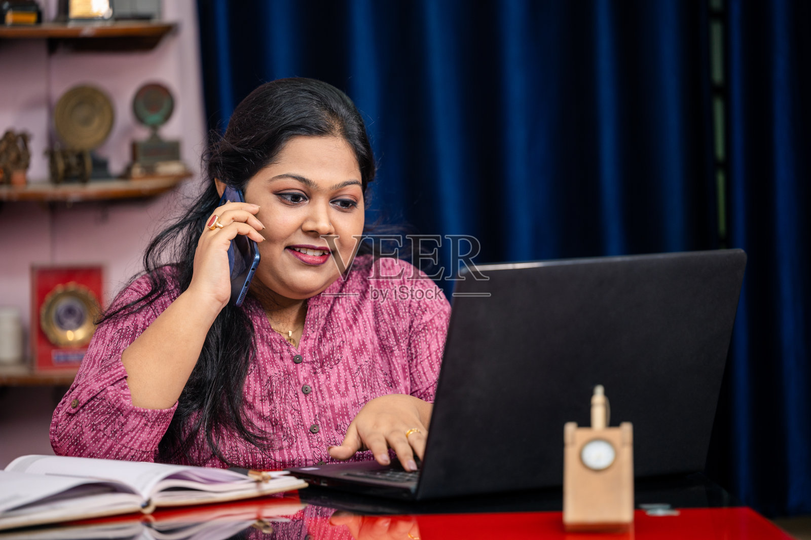 年轻的印度妇女在家工作，用手机打电话。照片摄影图片