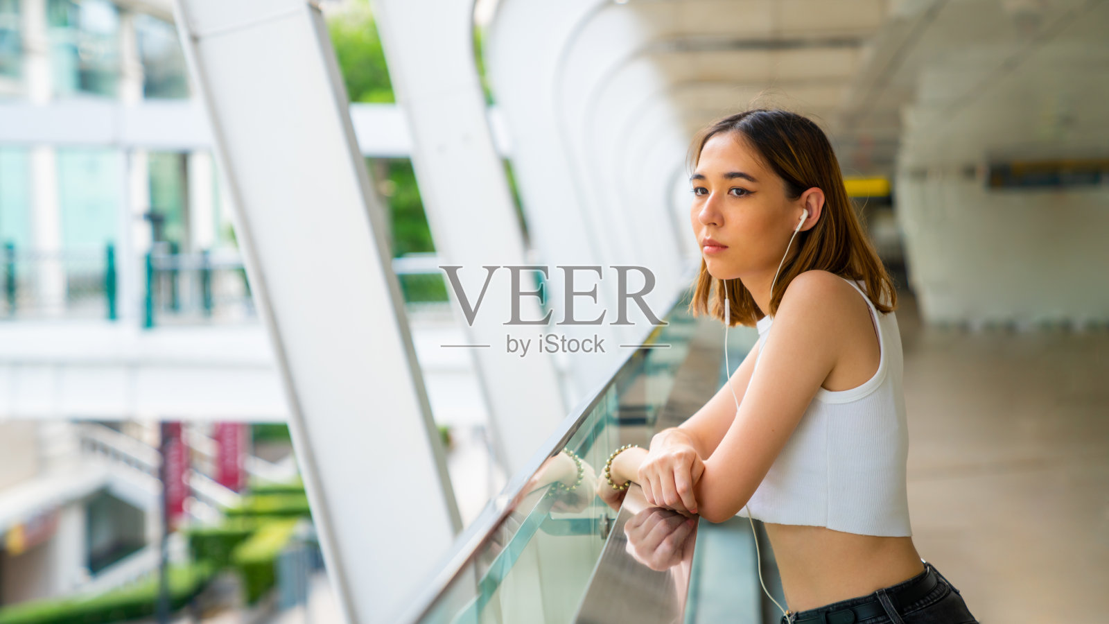 年轻的亚洲女人的肖像走在城市的街道听着音乐从耳机照片摄影图片