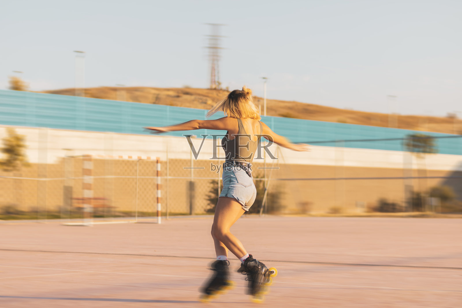 一个小女孩在户外的直排冰鞋上溜冰。照片摄影图片