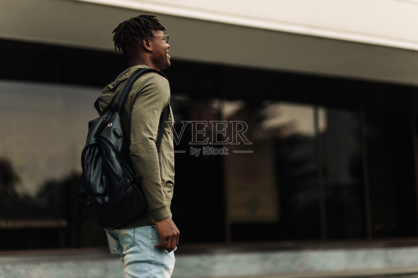 快乐成功的非洲学生，戴着眼镜，背着黑色背包，站在台阶上微笑照片摄影图片