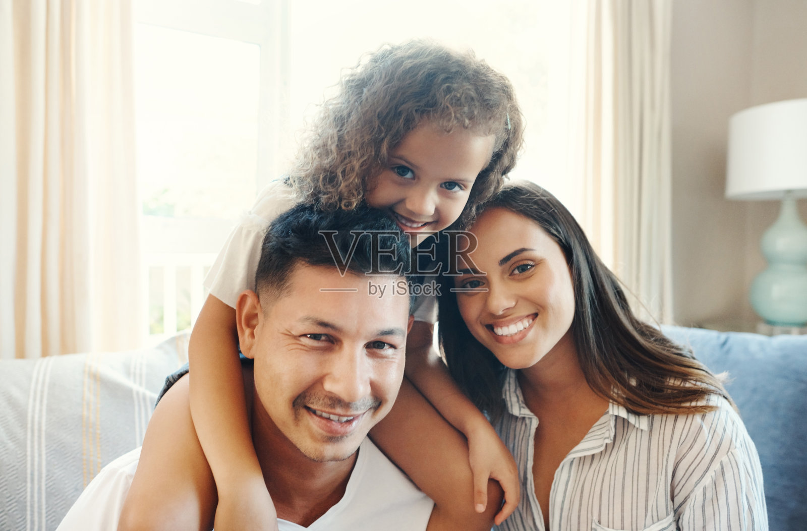 照片中，一对幸福的夫妇坐在沙发上，和他们的女儿亲密无间照片摄影图片