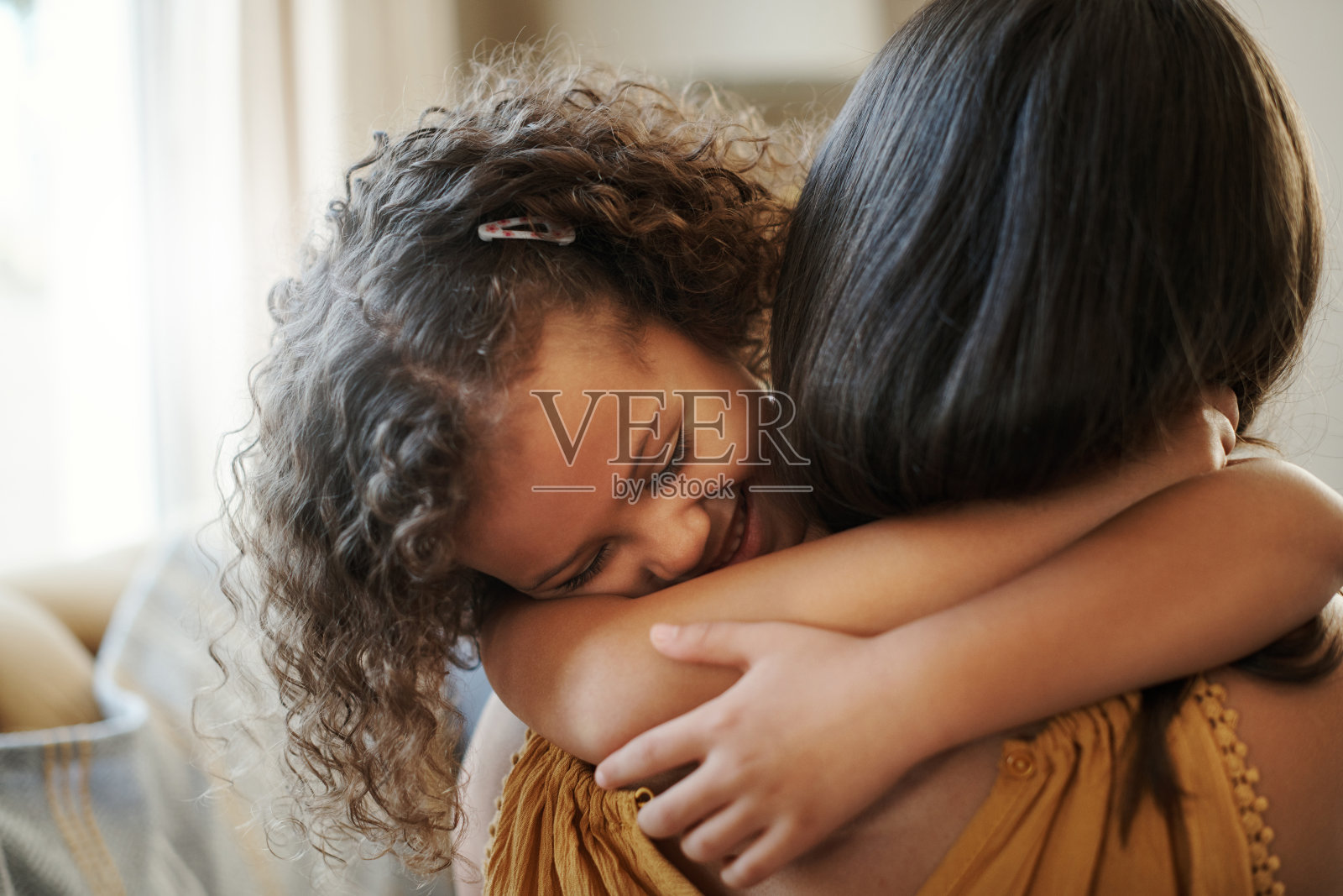 一个可爱的小女孩在家里的客厅里拥抱她的妈妈照片摄影图片