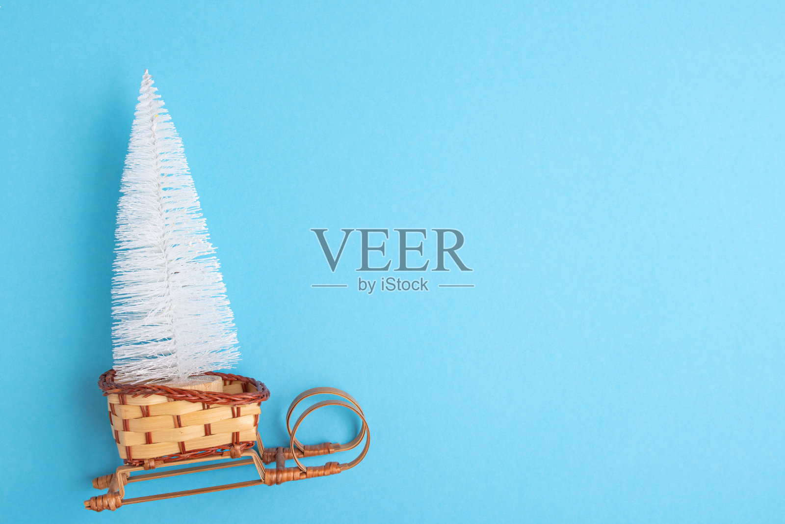 圣诞玩具白色云杉，杉树木制雪橇孤立在蓝色背景。创意最小的圣诞节和新年的艺术构成。复制空间，平铺。照片摄影图片