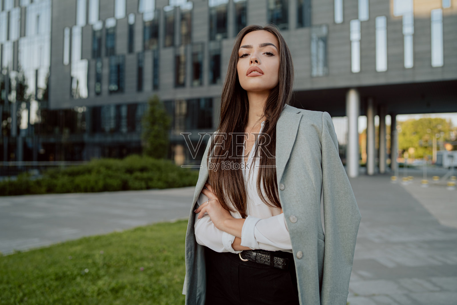 迷人的黑发女商人的肖像，秘书在日常化妆的女人穿着白衬衫和夹克扔在后面寒冷的早晨傍晚在玻璃公司办公楼前照片摄影图片