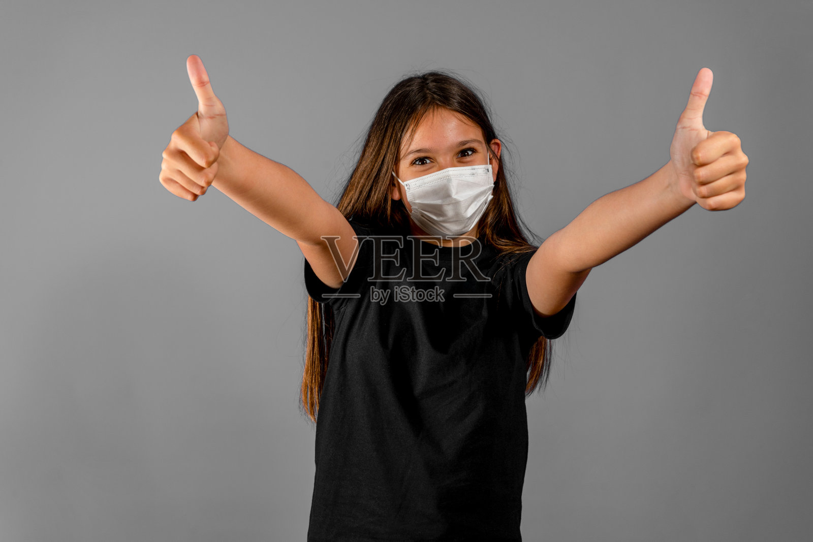 漂亮的照片深褐色长发女孩大拇指向上戴面部流感口罩黑色t恤孤立在灰色背景照片摄影图片