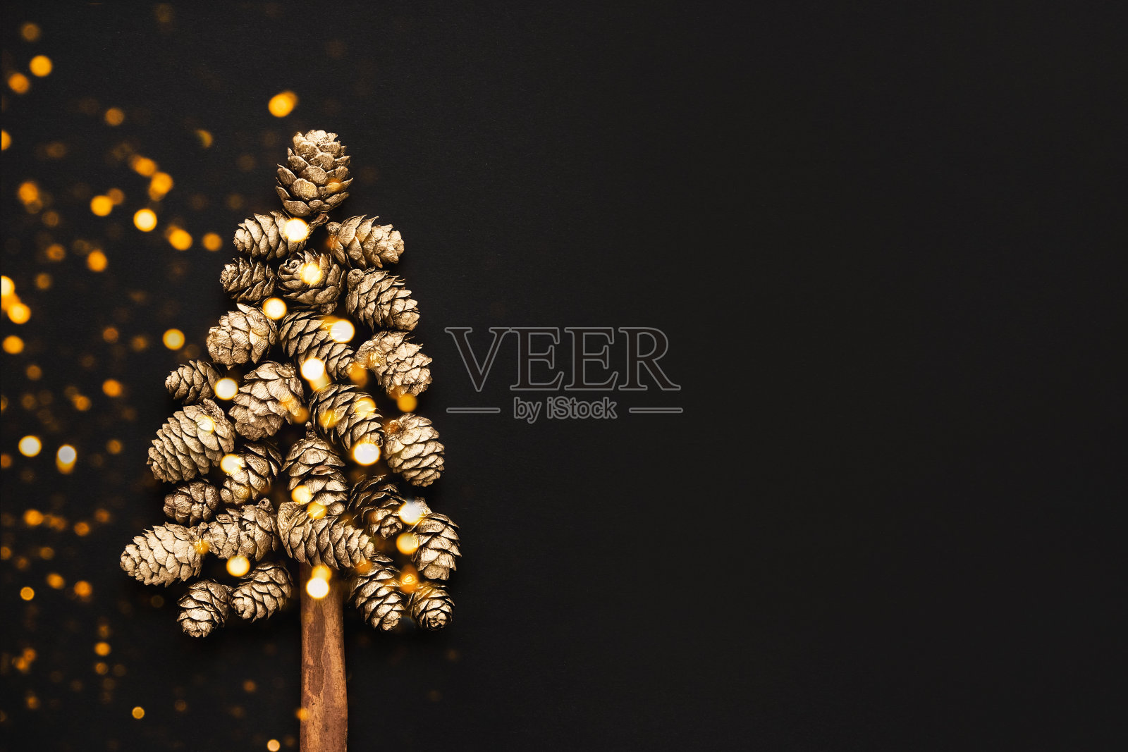 新年和圣诞贺卡。黑色背景下的金色圆锥形圣诞树。最小的新年概念照片摄影图片