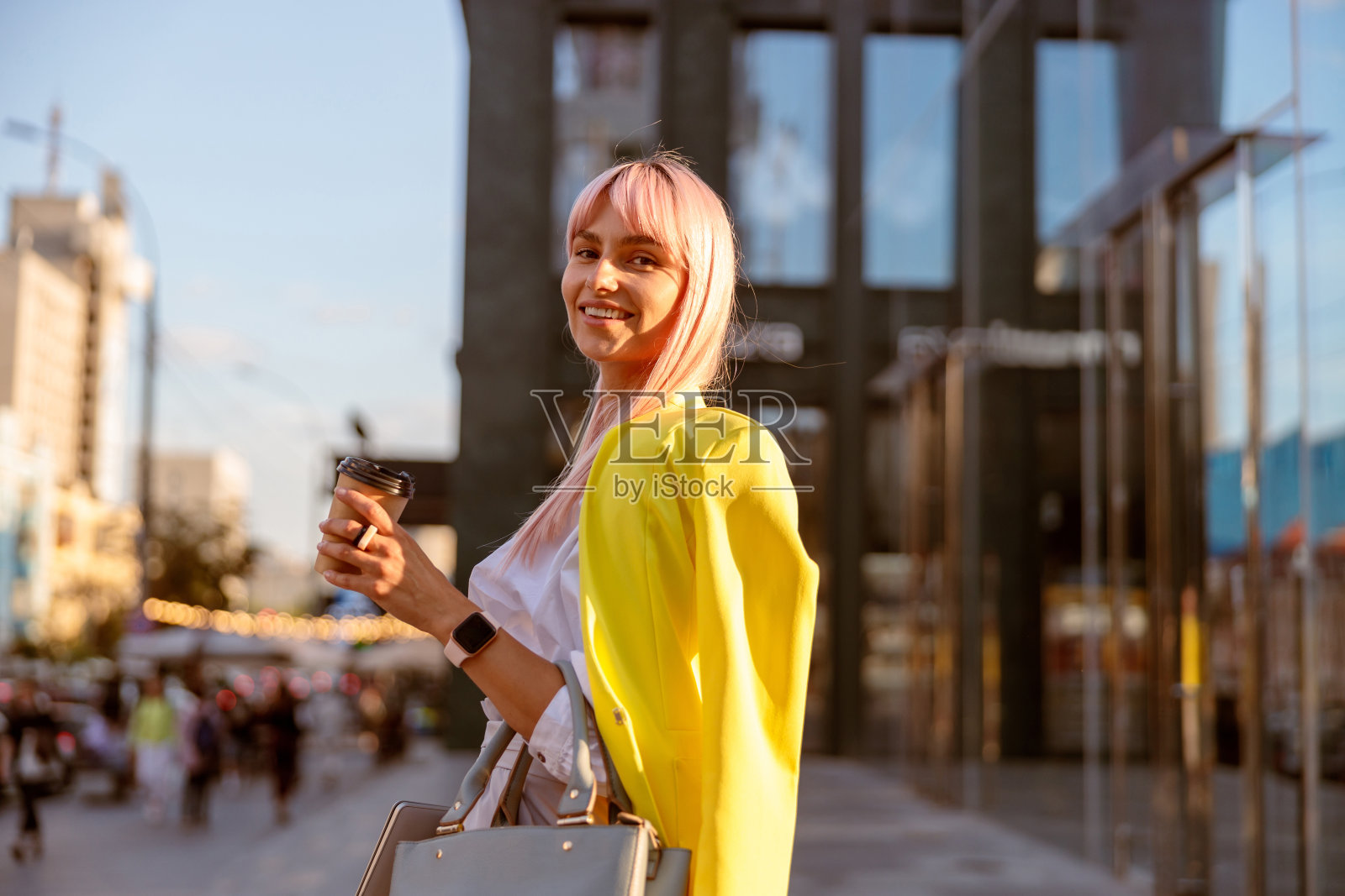 一个快乐的女人站在街上，手里拿着一杯咖啡照片摄影图片