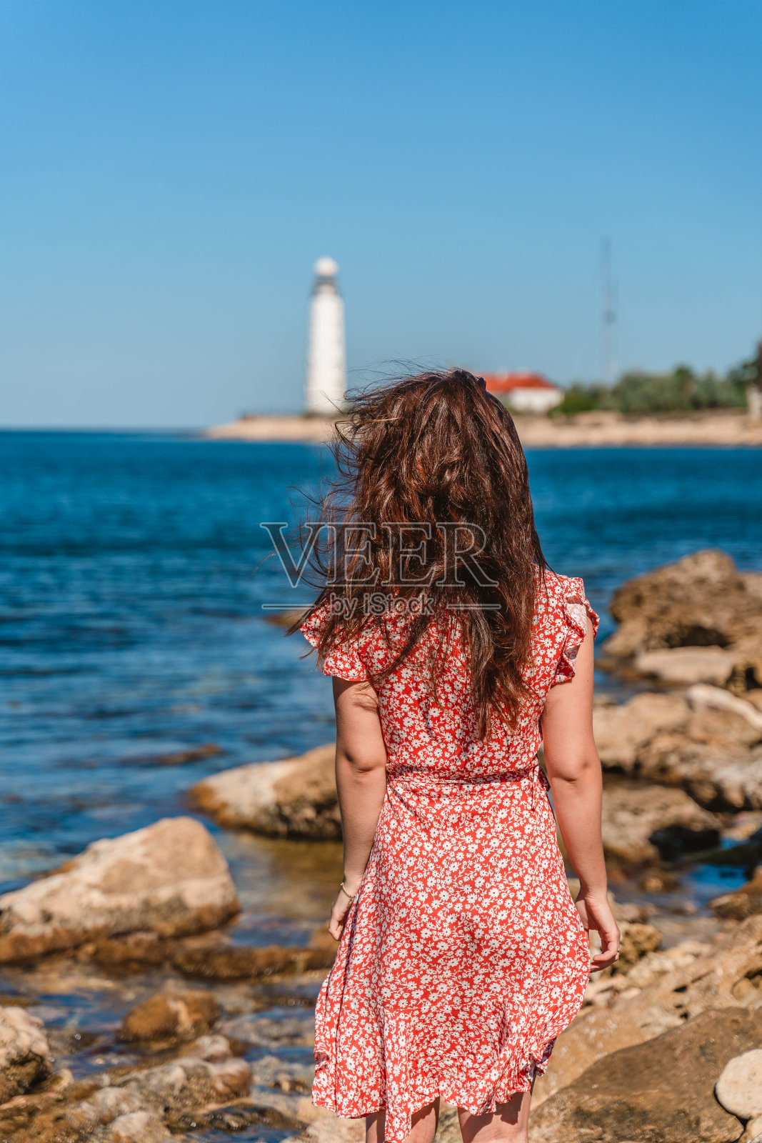一个迷人的年轻女子穿着裙子在黑海海岸远离切尔松索灯塔。克里米亚的夏日美景。照片摄影图片