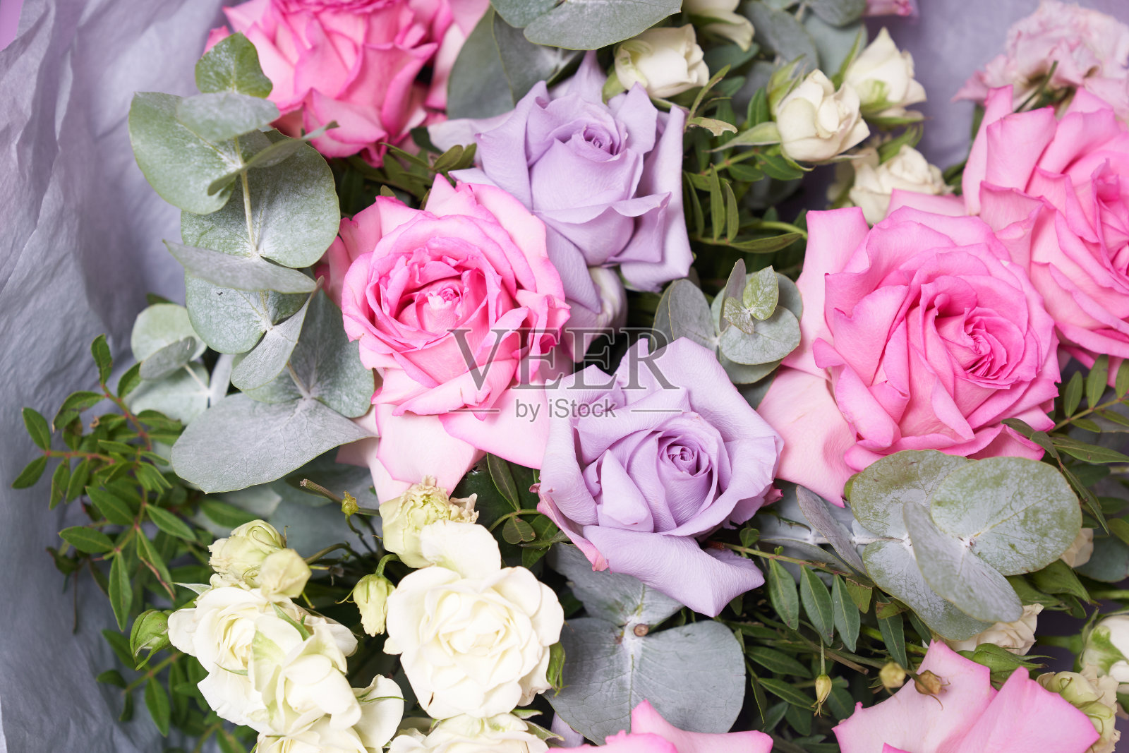 一大束五颜六色的花。大的粉红色玫瑰和桉树叶子。在一个浅色背景，侧视图。假期的概念照片摄影图片