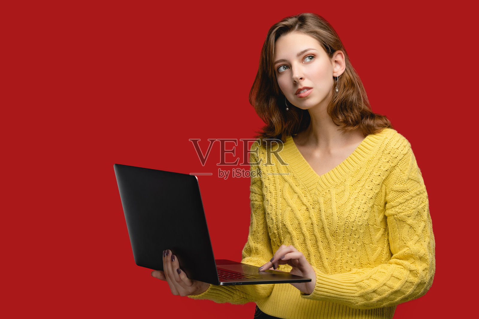 红色背景上的女人像，使用笔记本电脑在线工作的人。与现代观念的人，时尚女孩穿着黄色毛衣和工作自由。有复印空间的女人照片摄影图片