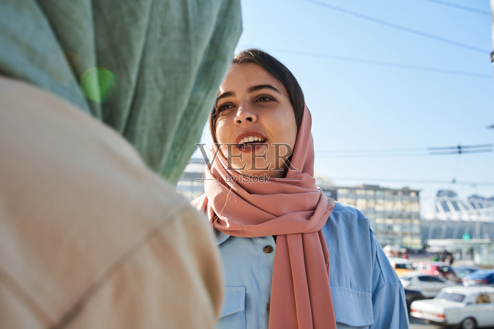 戴着头巾的友善阿拉伯女孩与她的女性闺蜜聊天照片摄影图片