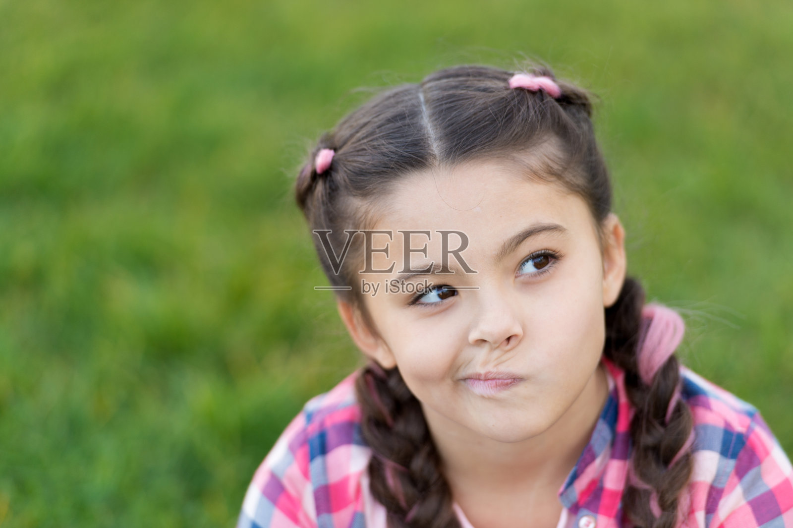 春天的概念。可爱的空想家。小女孩在公园户外休闲。女孩坐在公园的草地上。孩子们坐在公园的草地上，享受春天的阳光。公园和花园照片摄影图片