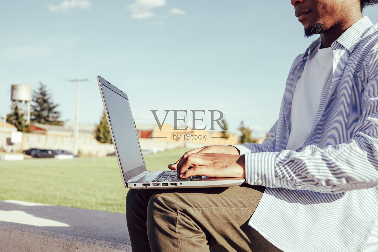 非洲裔美国人在公园的笔记本电脑上打字的特写照片摄影图片