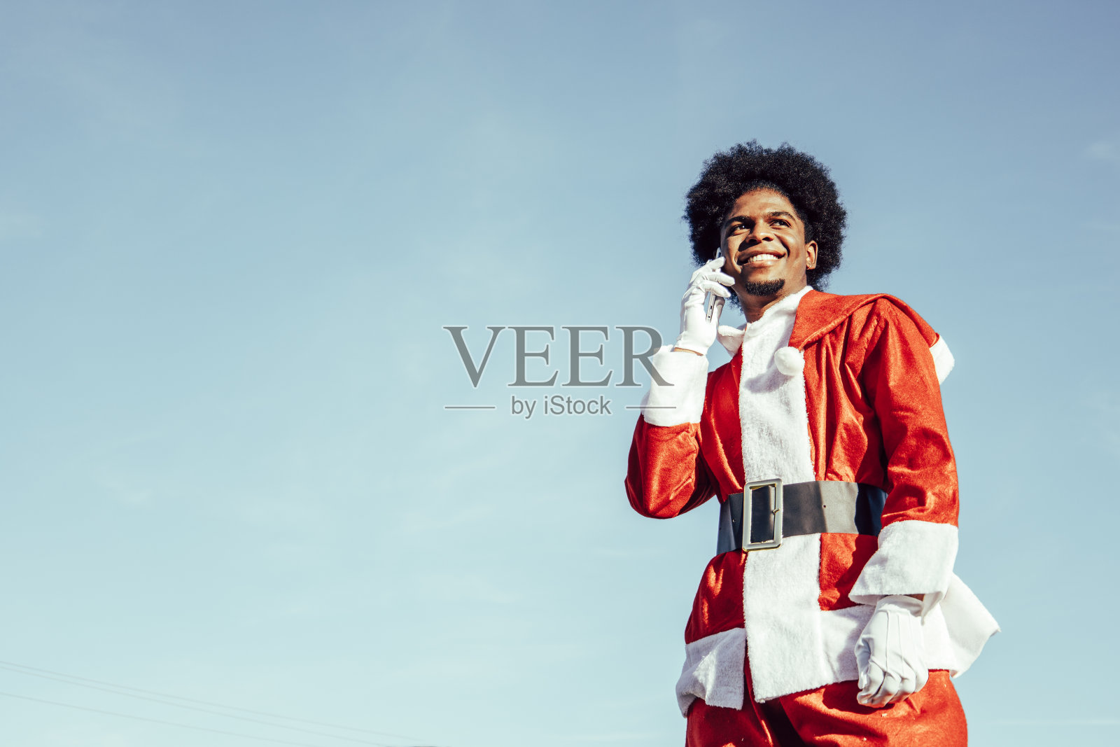 年轻的黑人圣诞老人在电话里说着话照片摄影图片