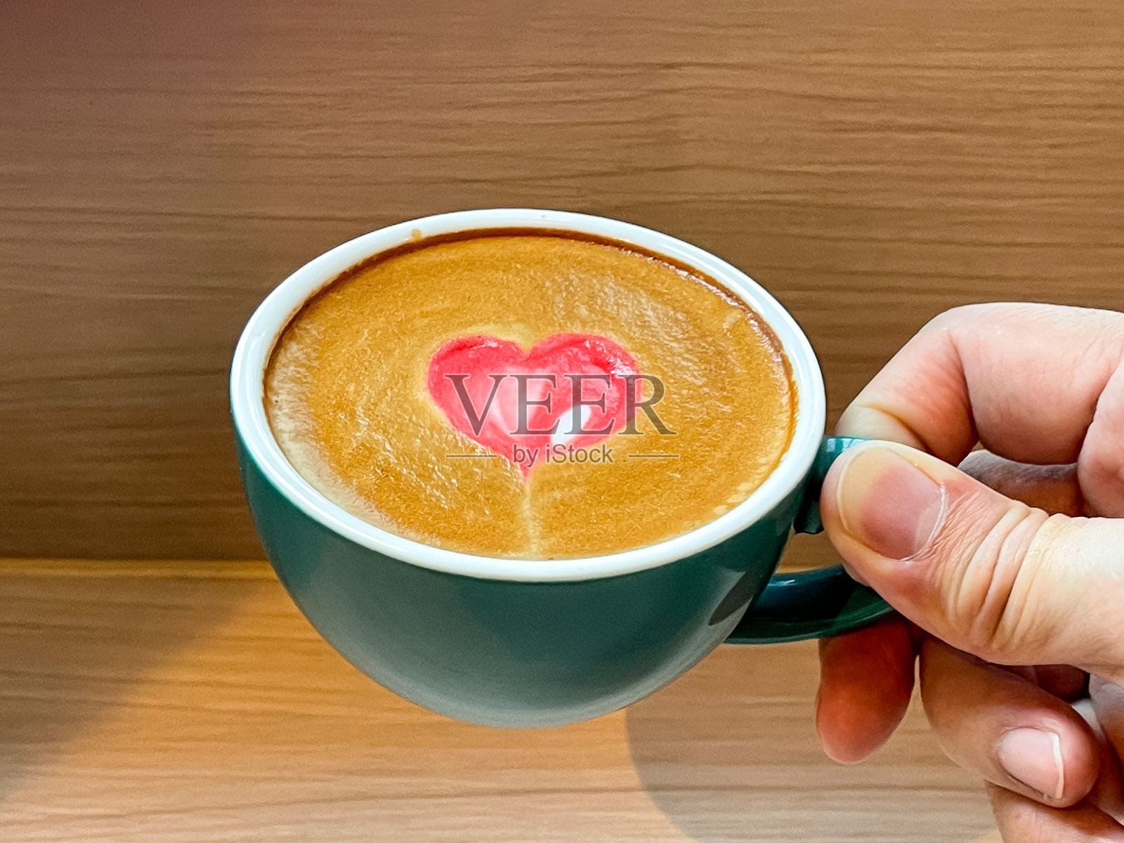 男人手里拿着一杯咖啡，后者带有红色的心形拉花艺术照片摄影图片