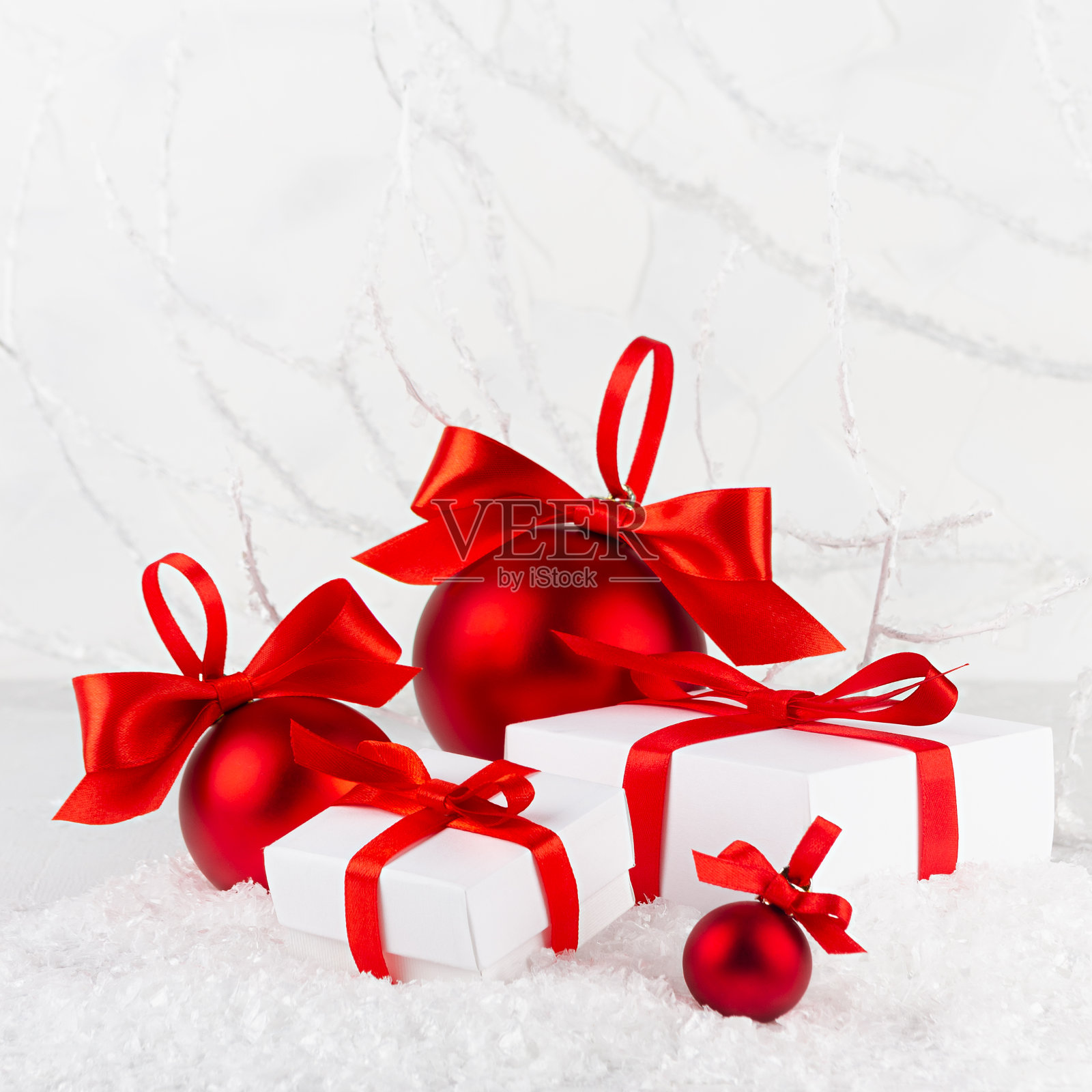 圣诞的喜庆背景在白色和红色的颜色闪烁球和缎带的礼品盒特写在雪堆下结霜的白色树枝，雪在冬天的森林，复制空间，广场。照片摄影图片