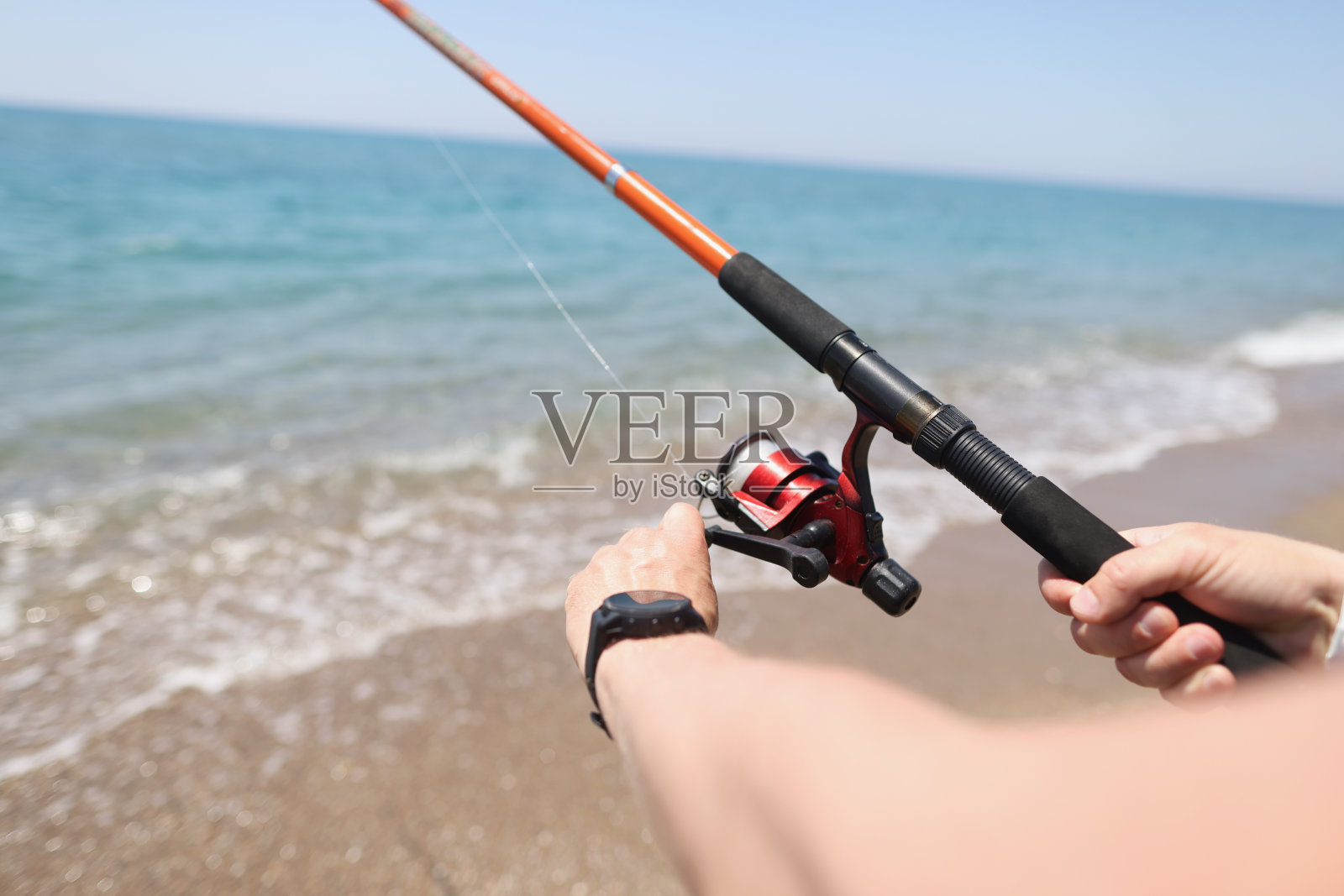 渔夫在海边用鱼竿钓鱼的特写照片摄影图片