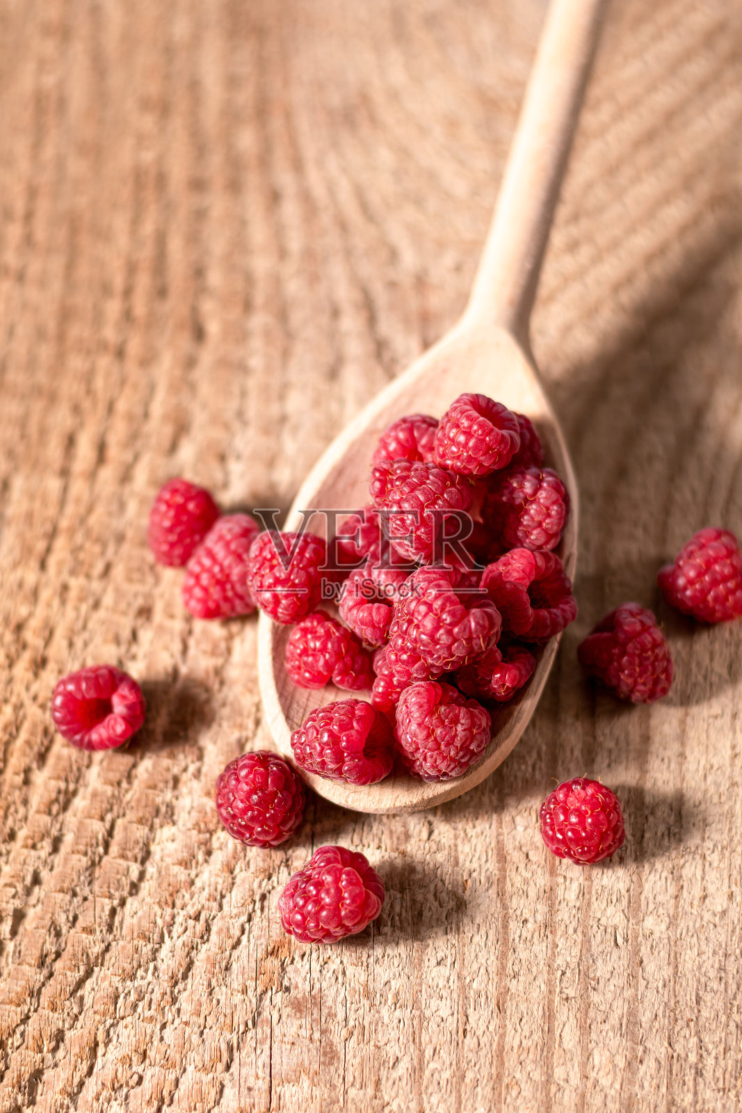 木勺上的成熟红覆盆子，木制背景。满木勺的新鲜覆盆子。照片摄影图片