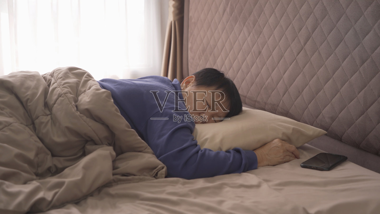 昏昏欲睡的老亚洲女人，人们一大早就躺在家里卧室的床上睡觉。生活方式照片摄影图片