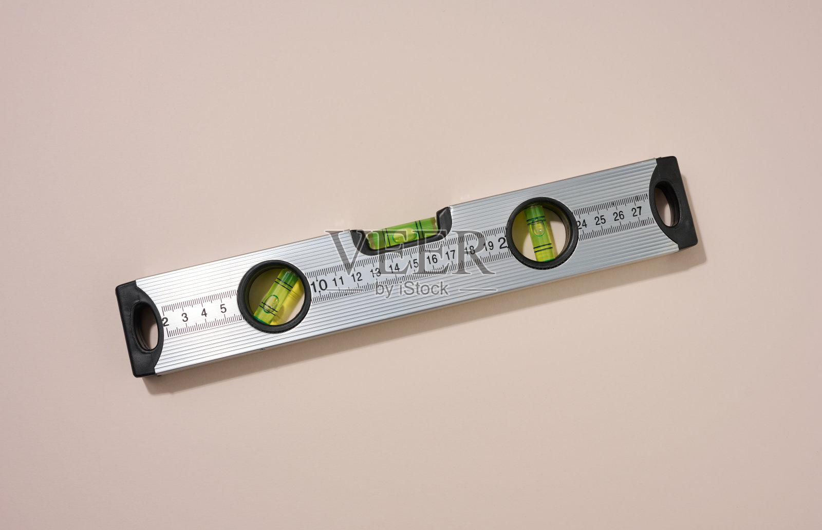 米色背景上的金属建筑水平。测量仪器照片摄影图片