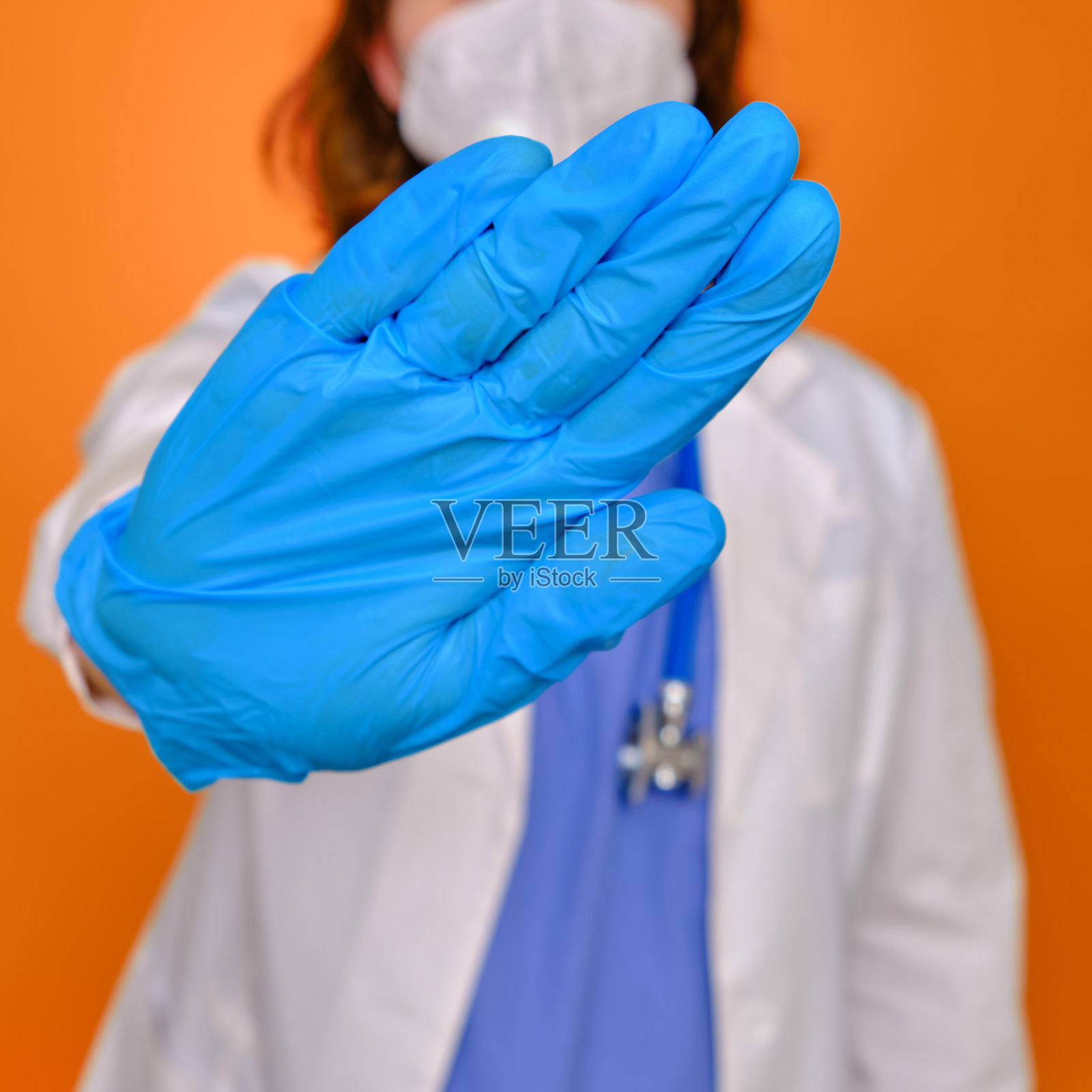 医生用手做出拒绝的手势，留在家里。红色背景下的女医生，特写镜头照片摄影图片